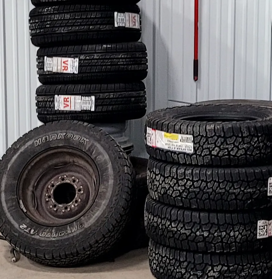 Stacks of new tires with their labels still on, beside a mounted wheel