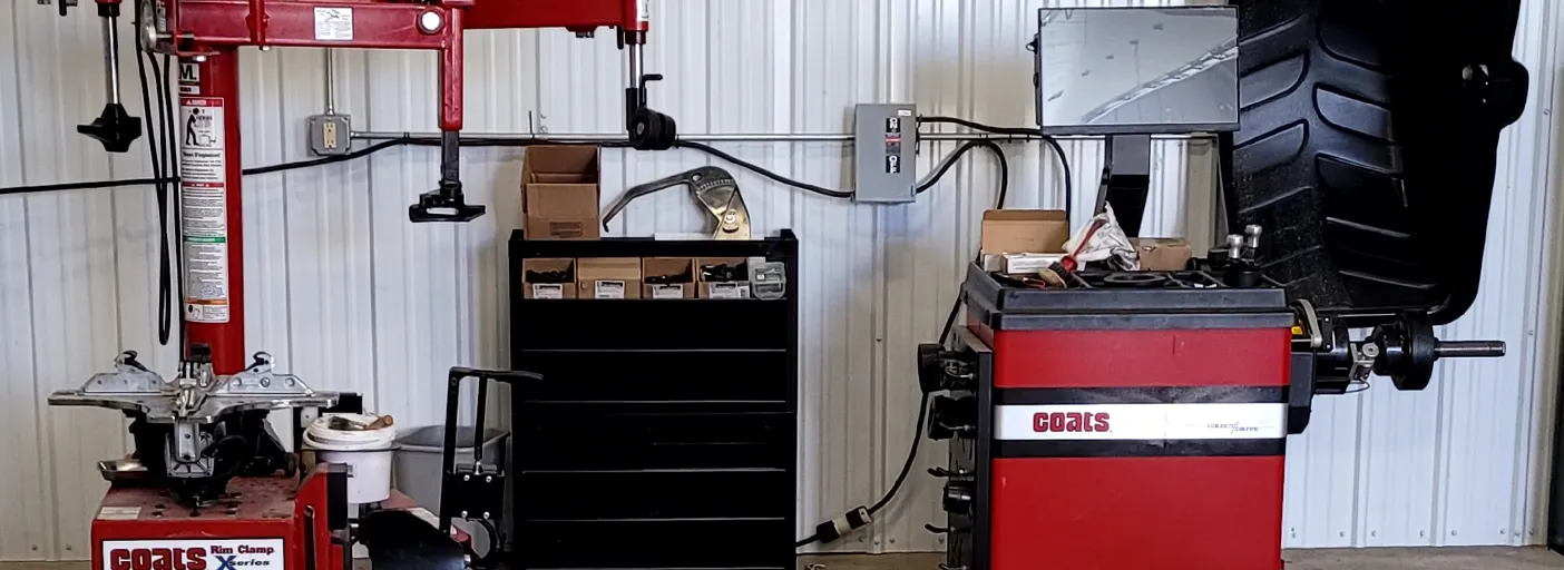 A red tire changer and a red wheel balancer against the white shop wall